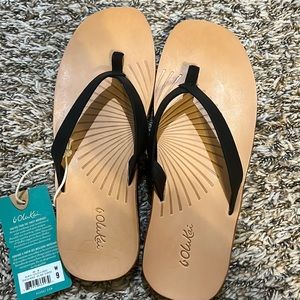 Olukai Womens lwi black-golden sand leather flip flop